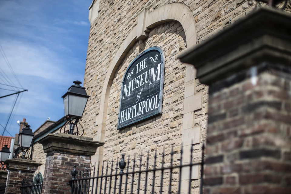 Museum of Hartlepool sign on a brick wall with old-fashioned lantern in front.