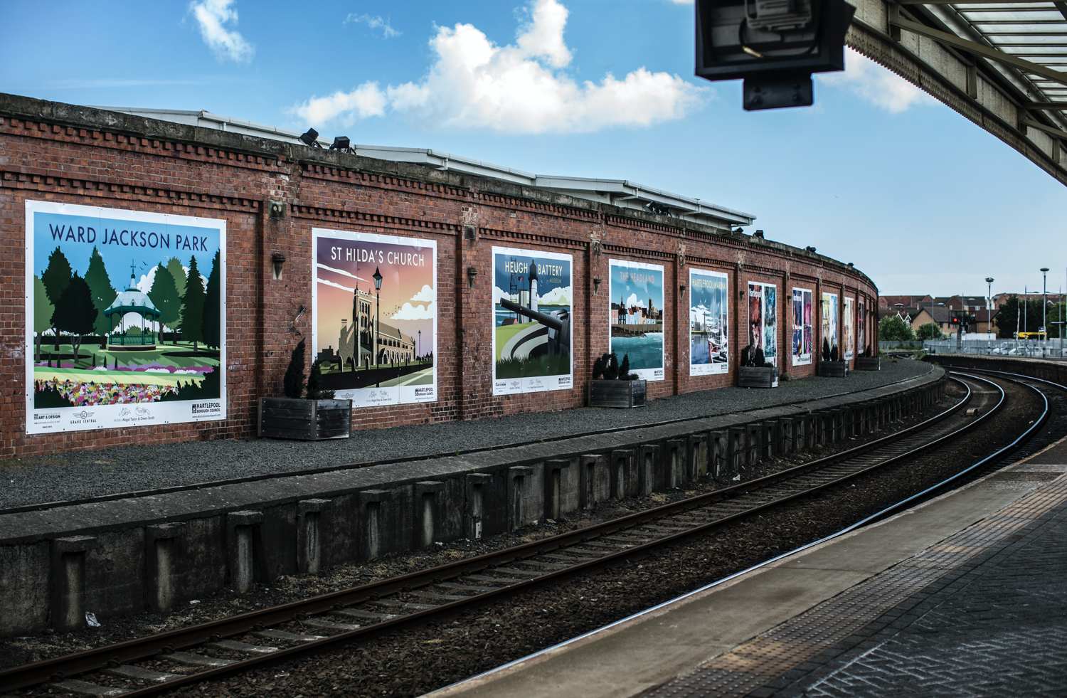 A curved brick train station platform with vintage-style posters advertising local landmarks.