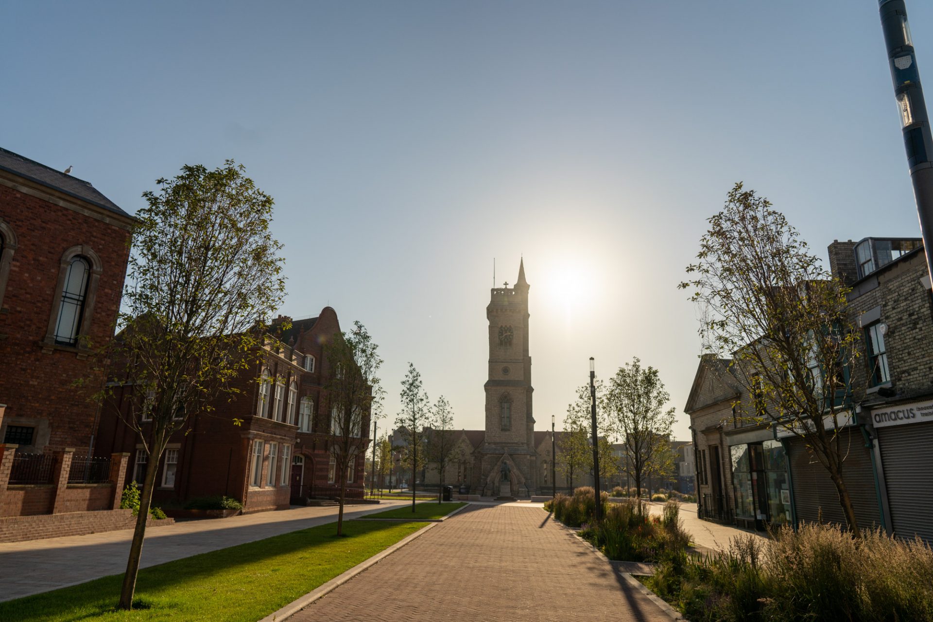 A stone church with a tall clock tower and arched entrance surrounded by grass.