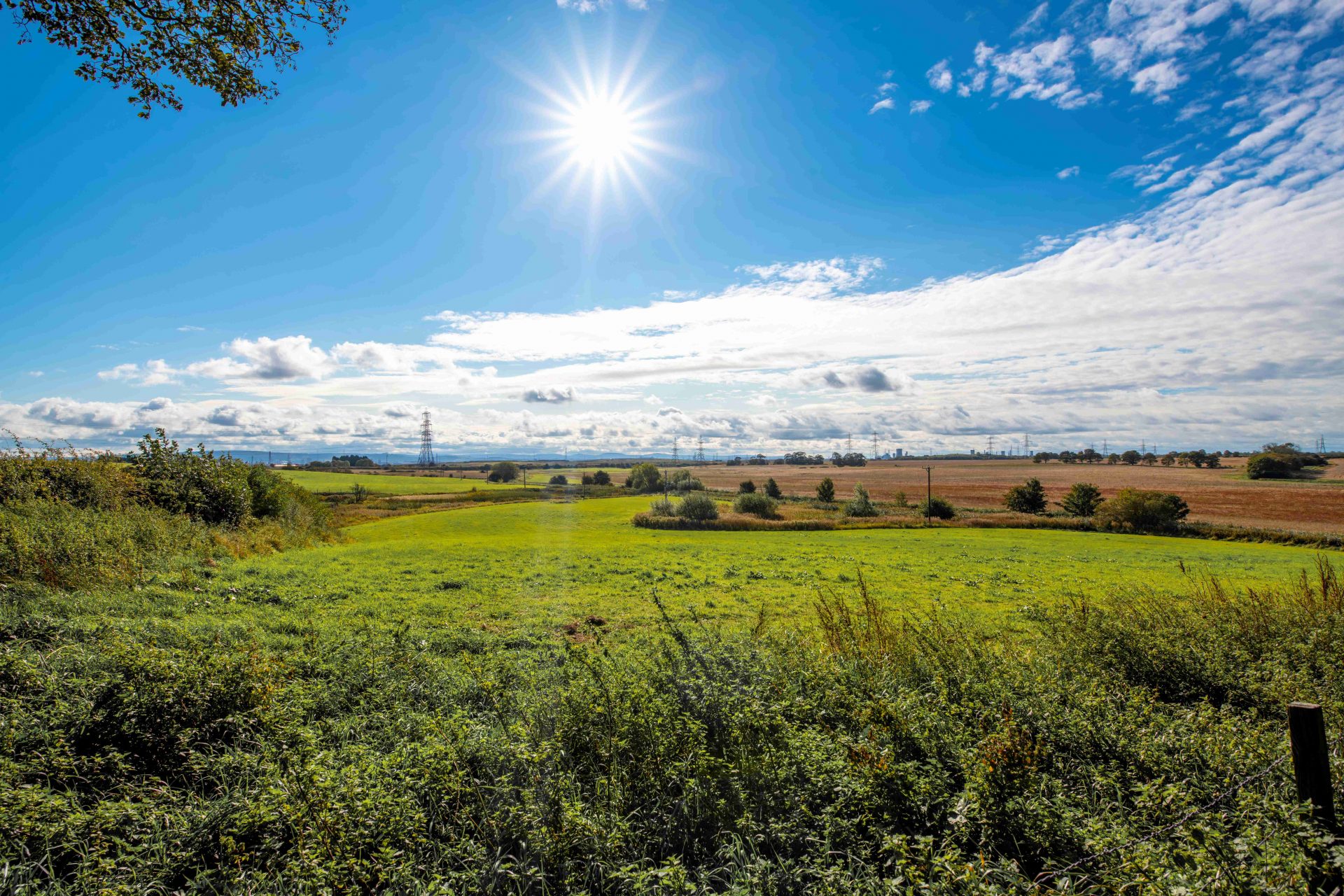 A view across fields and open countryside with blue sky on a sunny day.