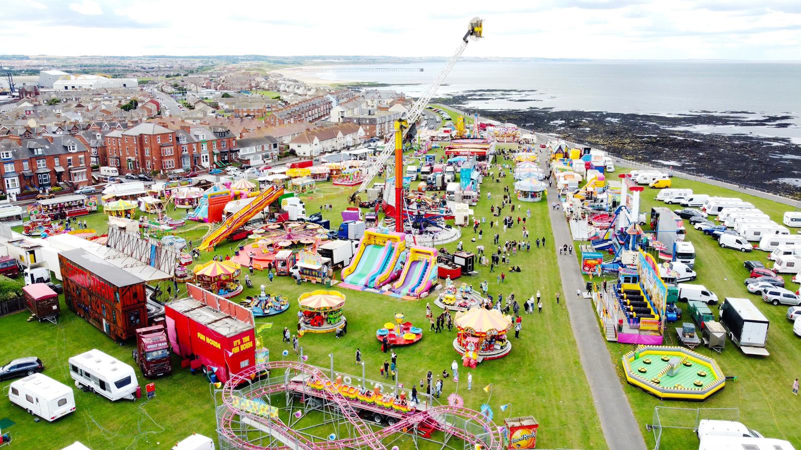 Aerial photo Headland Carnival with attractions in the foreground and the sea in the background.